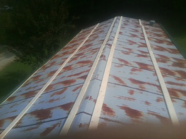 Rusted metal roof panels with new wood purlins before replacement — Storm Damage Roof Repair in West Liberty by Roofing Brothers